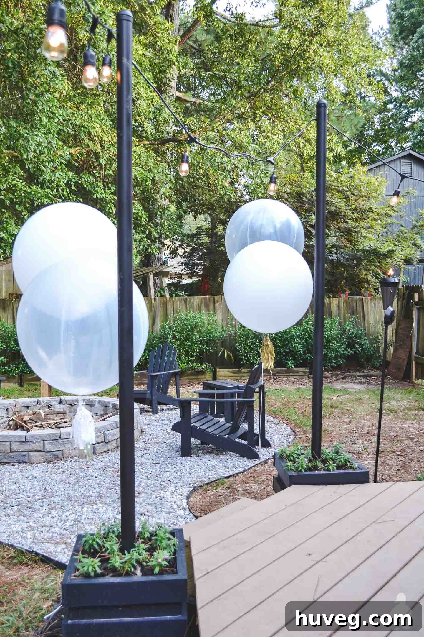 backyard light poles with black chairs around fire pit