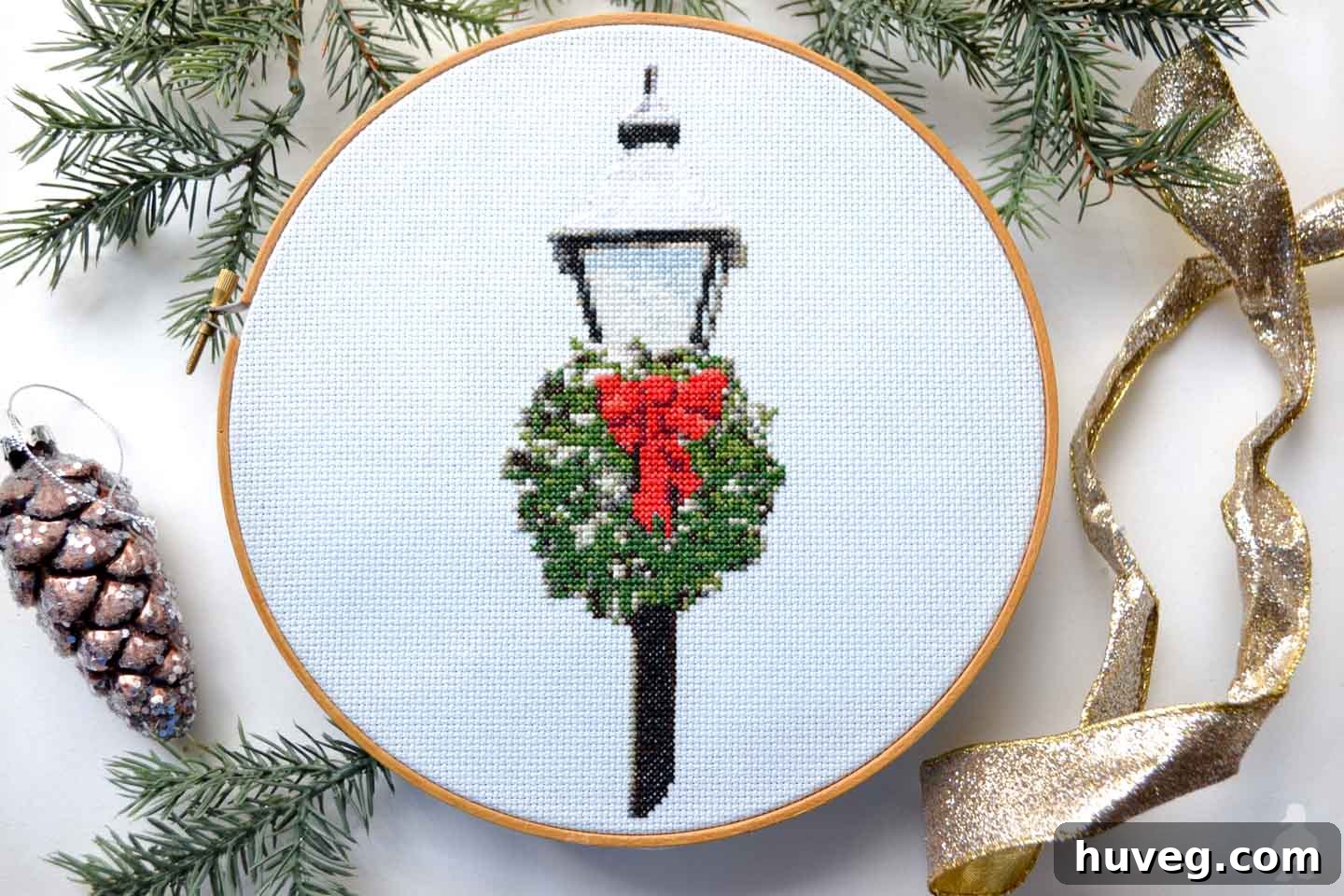 Close-up of stitched Christmas lamppost cross stitch pattern with red bow and green wreath
