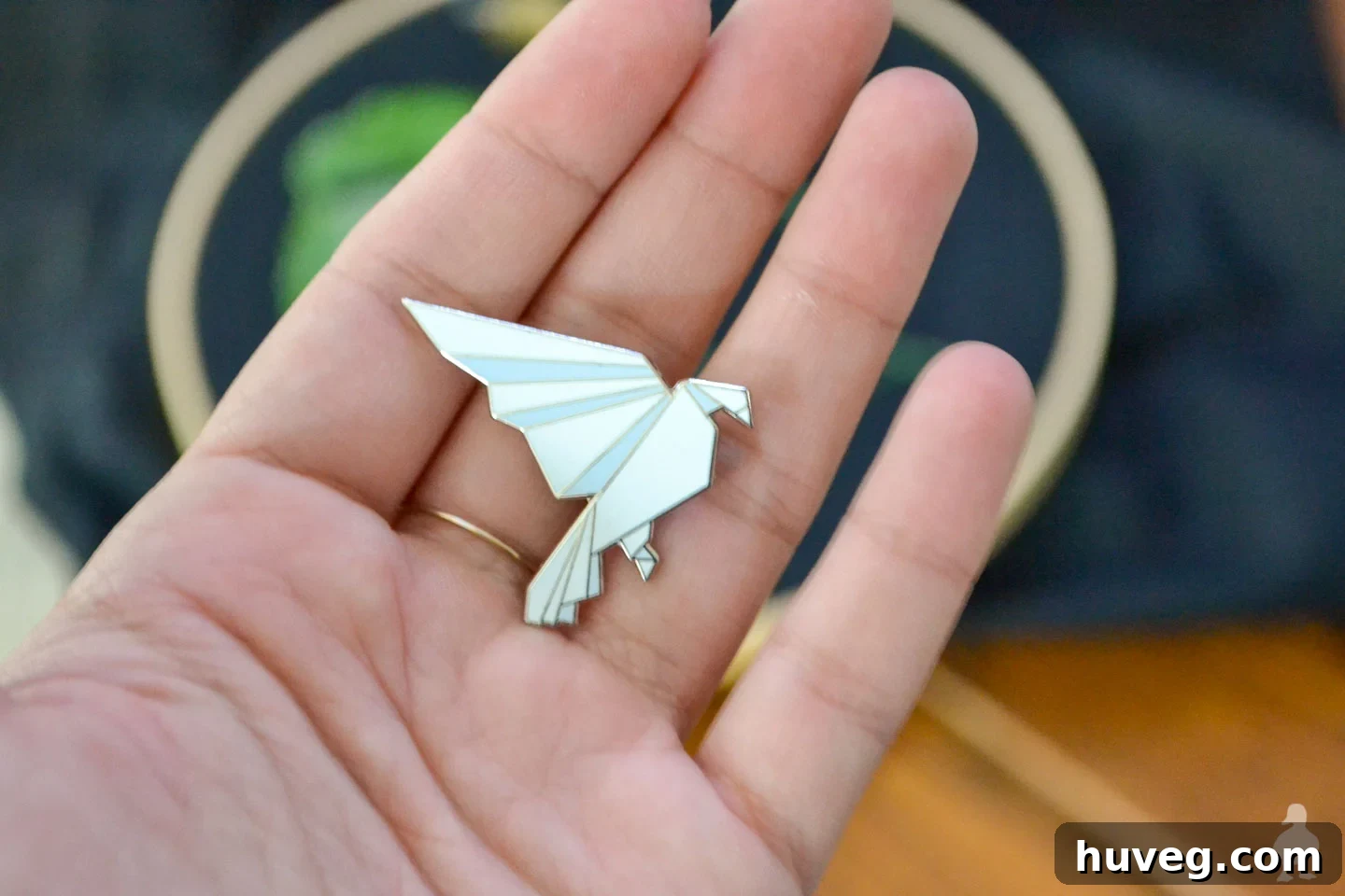 Holding a white origami lapel pin, ready for conversion into a needle minder.