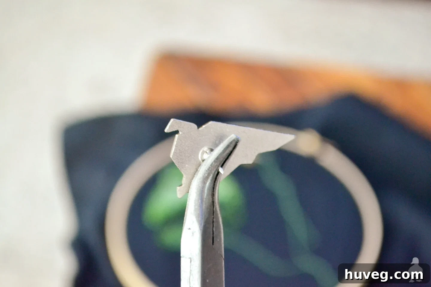 Carefully removing the back prong from a lapel pin using cutting pliers.