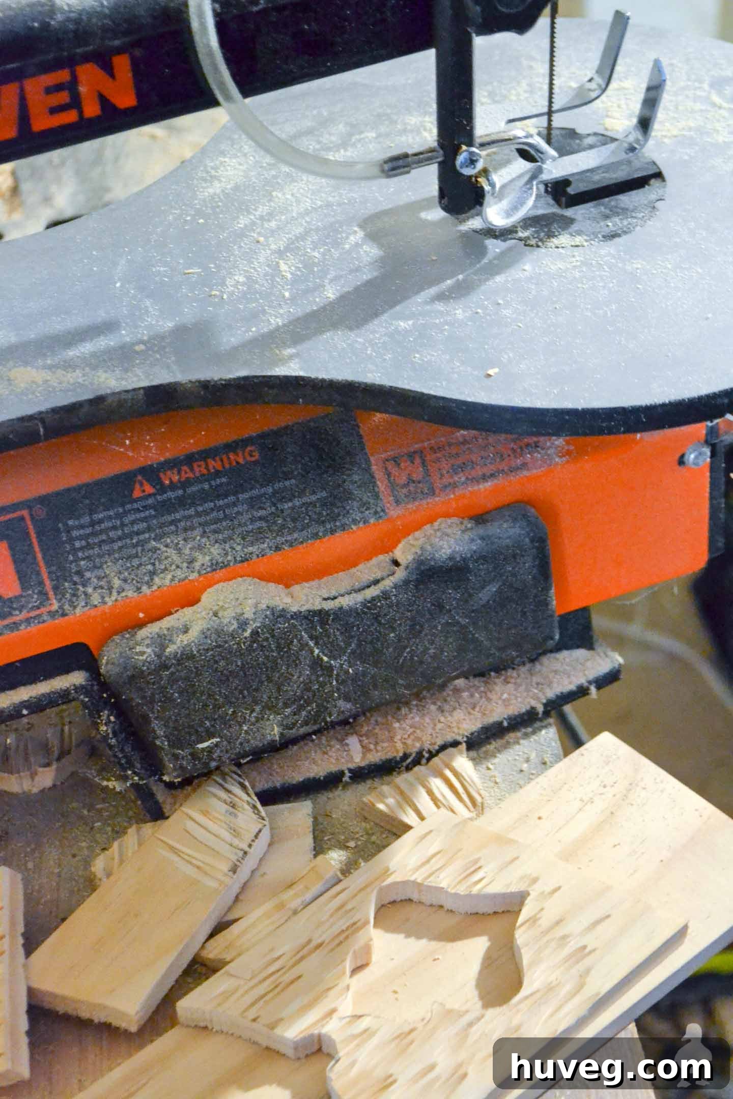 Close-up shot of a scroll saw in action, precisely cutting a wood ornament shape. Essential for intricate designs in DIY rustic wood ornaments.