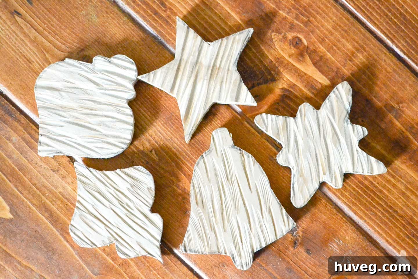 Freshly cut wooden ornament shapes lie on a surface, showcasing the precise cuts made by a scroll saw, ready for the next steps in creating DIY rustic wood ornaments.