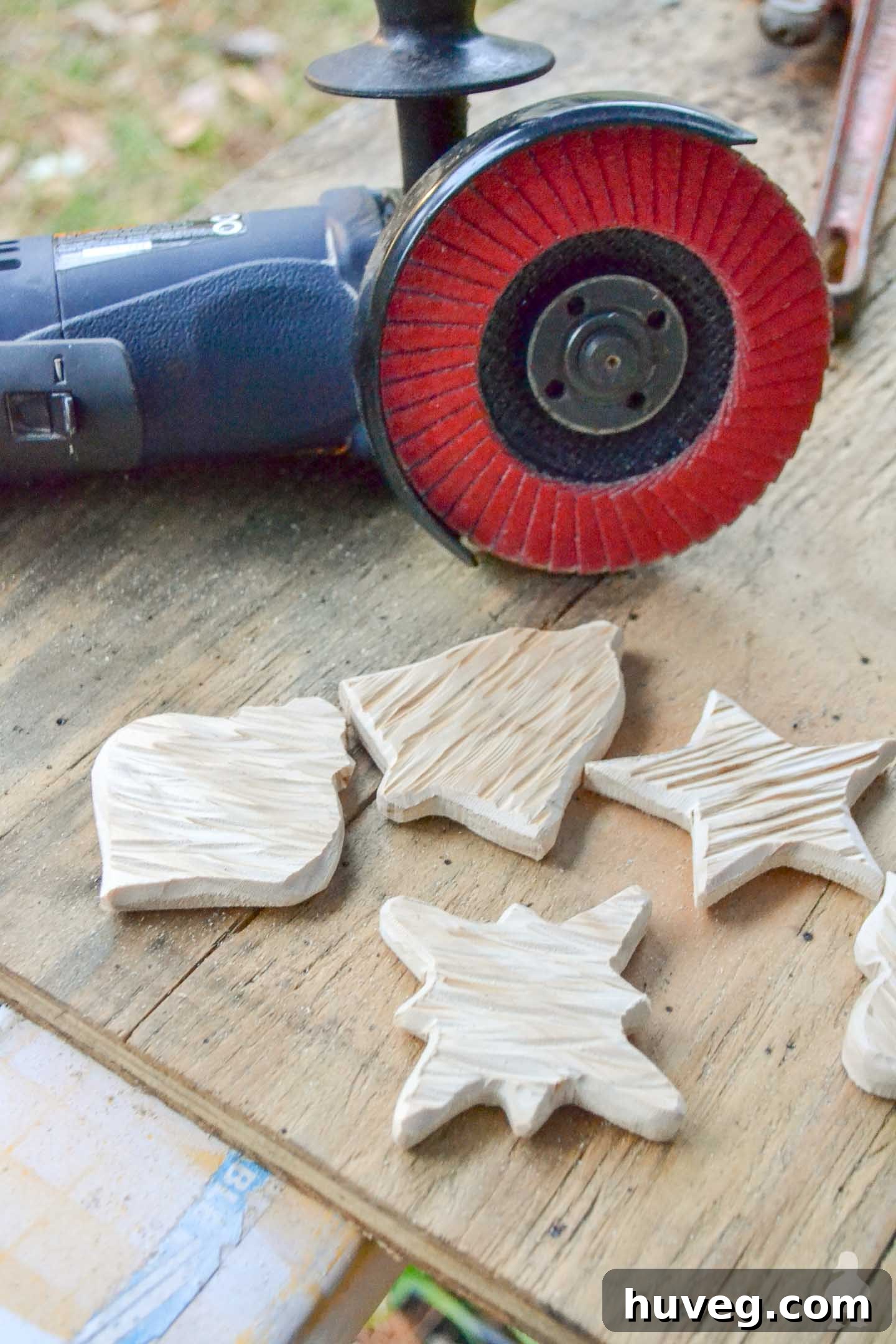 An angle grinder is used to meticulously rough up the edges of freshly cut wooden ornaments, creating a worn, rustic texture perfect for DIY wood decor.