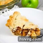 classic brandy apple pie slice on white plate with granny smith apple