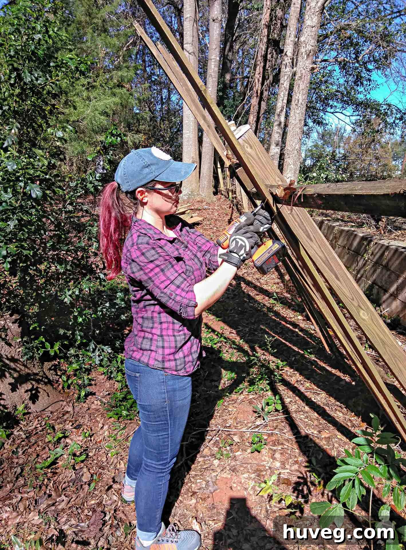 Dismantling a long, broken fence line damaged by storm, showing focused work.