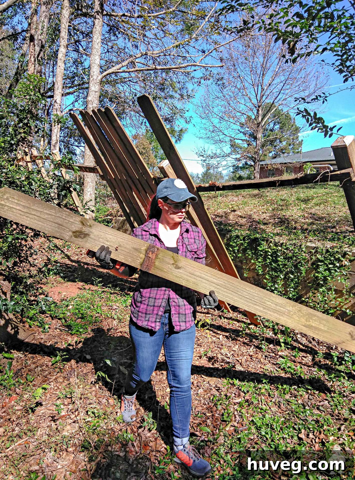 Carrying heavy fence panels away from the damaged area after storm cleanup.