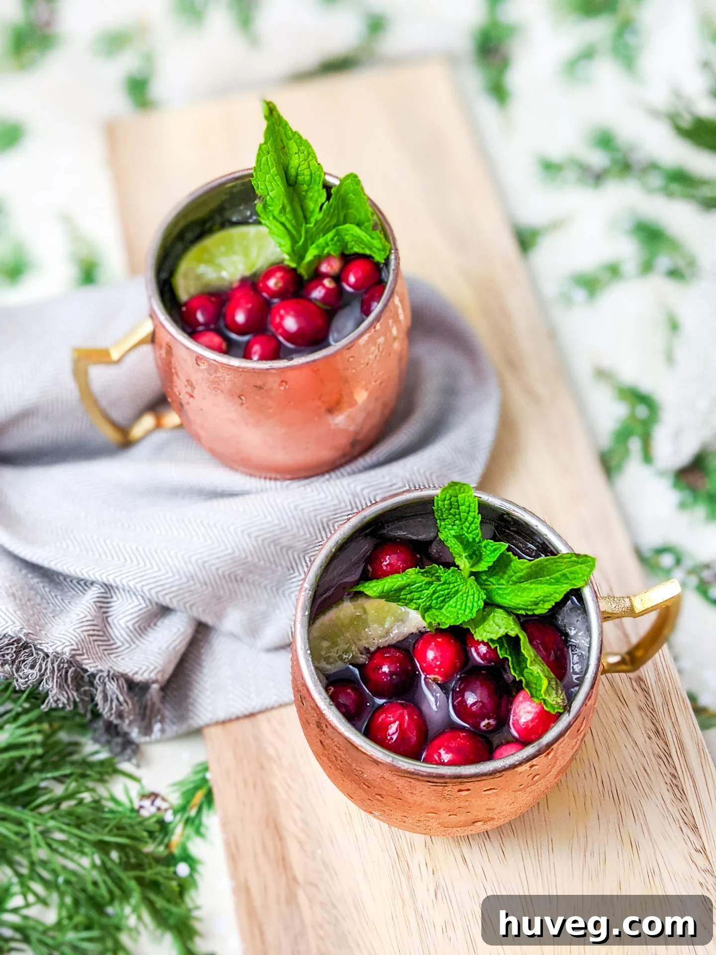Spiced sparkling cranberry Moscow mule on Christmas background with mint and lime garnish, representing a festive watercolor style