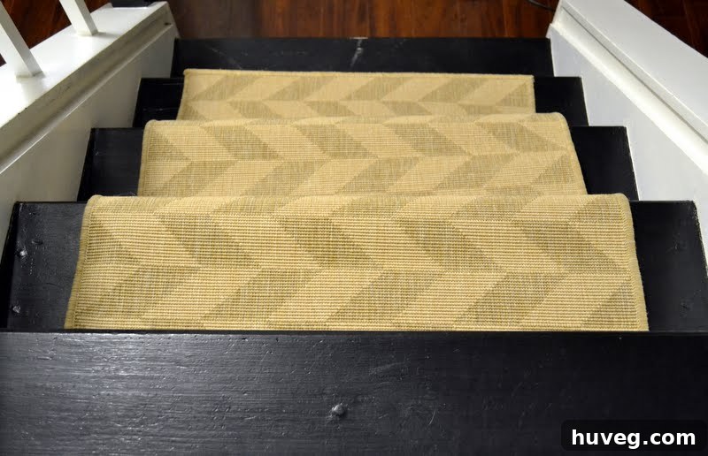 A beige test stair runner laid loosely on black painted stairs, illustrating a design trial in progress.