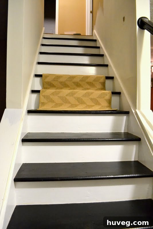 A full view of the black painted staircase with a beige test runner temporarily placed, highlighting the color contrast with the surrounding walls.
