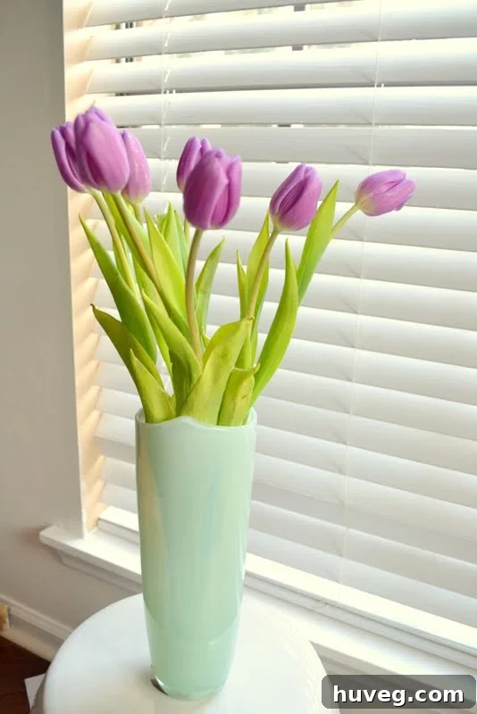 A beautifully bright living room with abundant natural light, showcasing fresh tulips in a teal vase on a coffee table, signifying a successful home transformation.