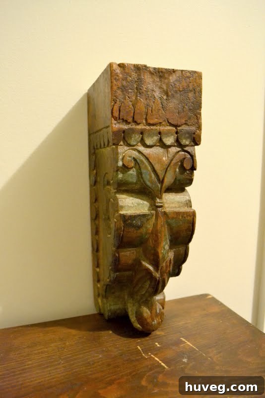 An old, weathered corbel propped against an entryway wall, hinting at its future placement and the thoughtful process of home decorating.