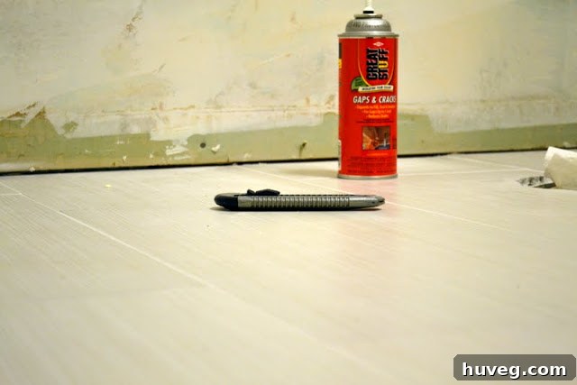 Two cans of GREAT STUFF expanding foam sealant on a wooden surface with a measuring tape