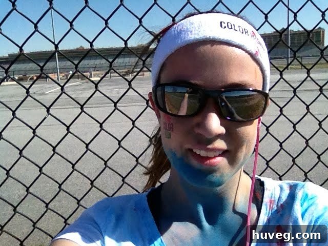 Being enthusiastically dusted with blue powder at a color station during The Color Run, covering chin and face.