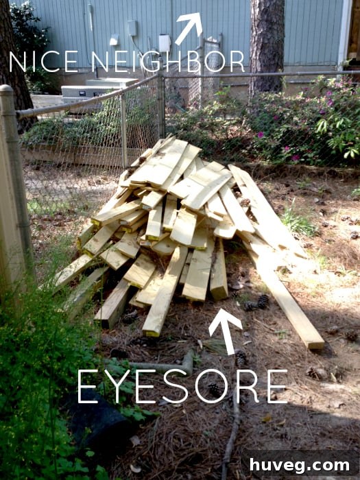 A pile of wooden fence posts, planks, and other construction materials sitting in a backyard, waiting to be used.