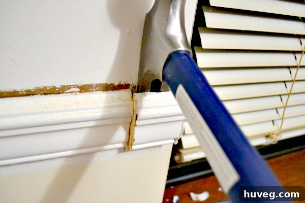 Carefully prying trim off the wall