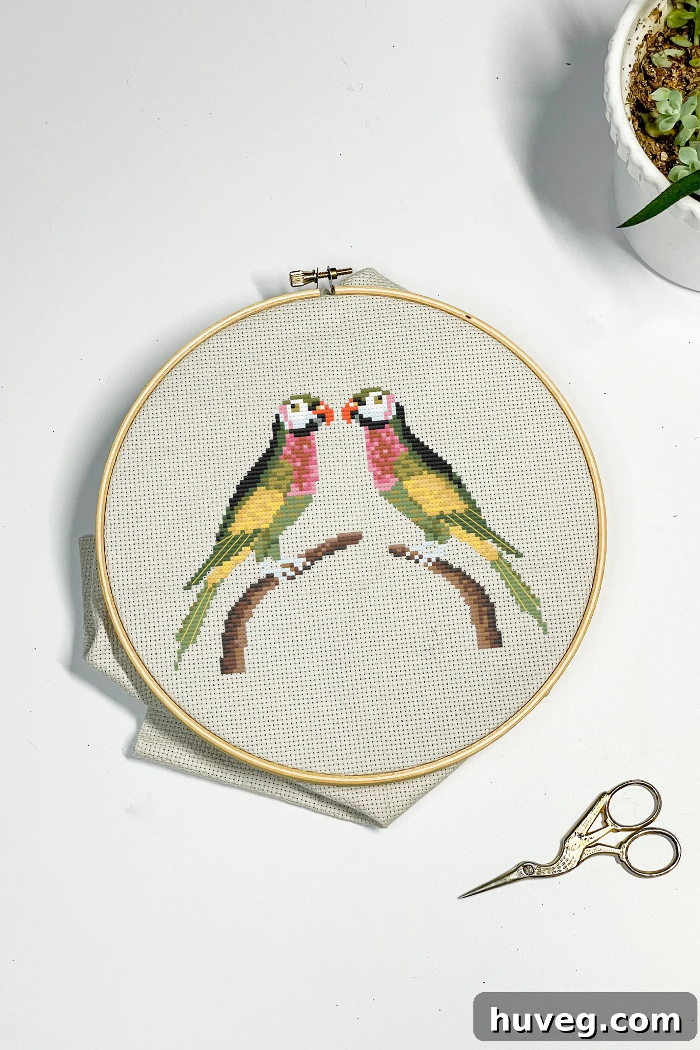 Detail view of lovebirds cross stitch pattern on Aida cloth.
