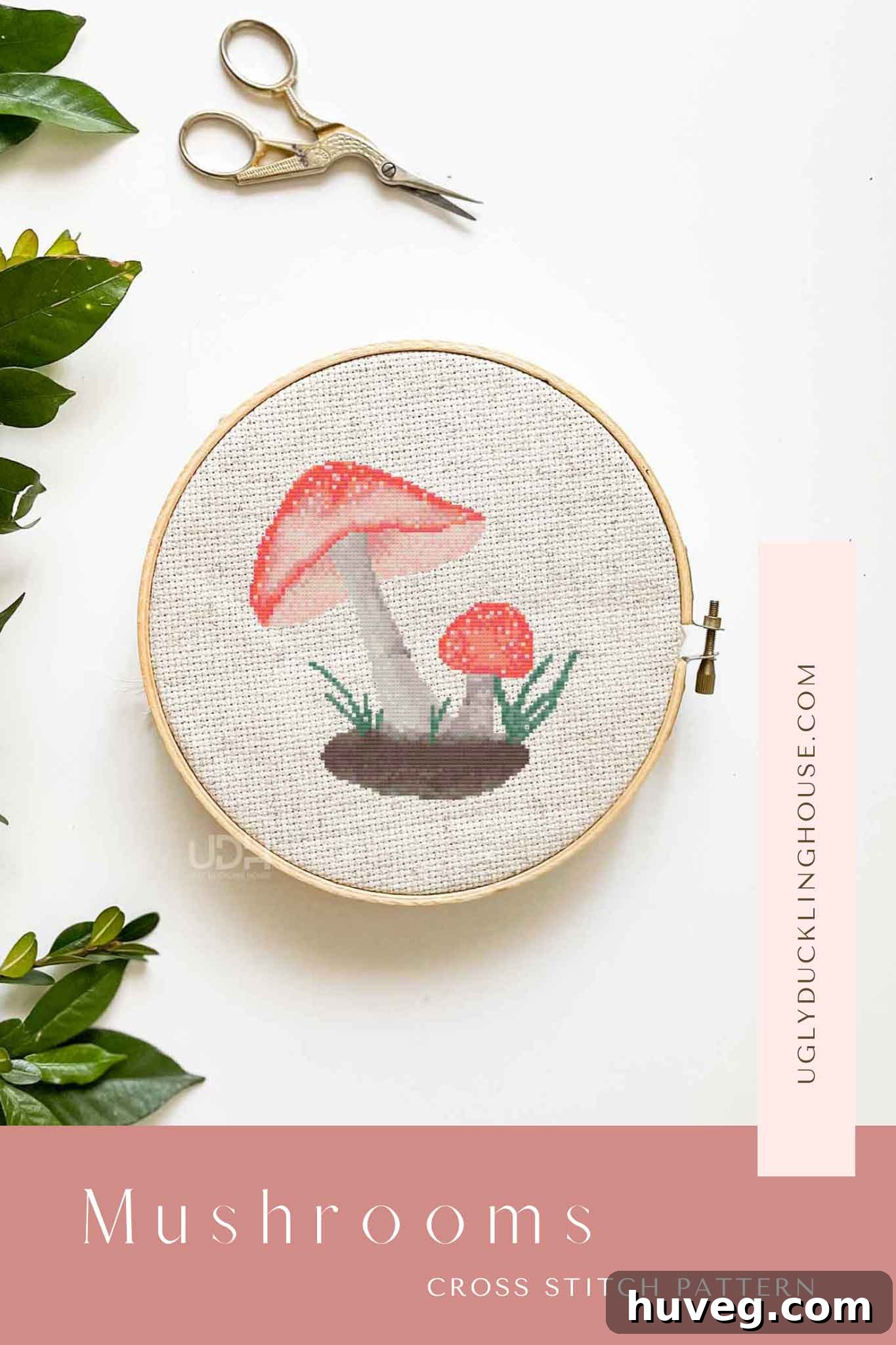 Whimsical mushroom cross stitch hoop on a white background with decorative leaves and scissors, ready for your next project.