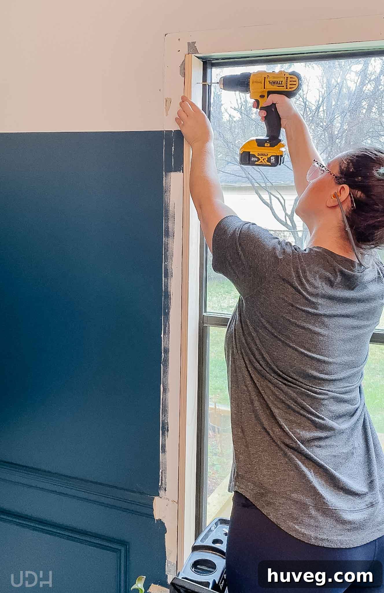 Me carefully inserting the wooden wrap that fits inside the window frame and screwing it to the inner framing for a snug fit