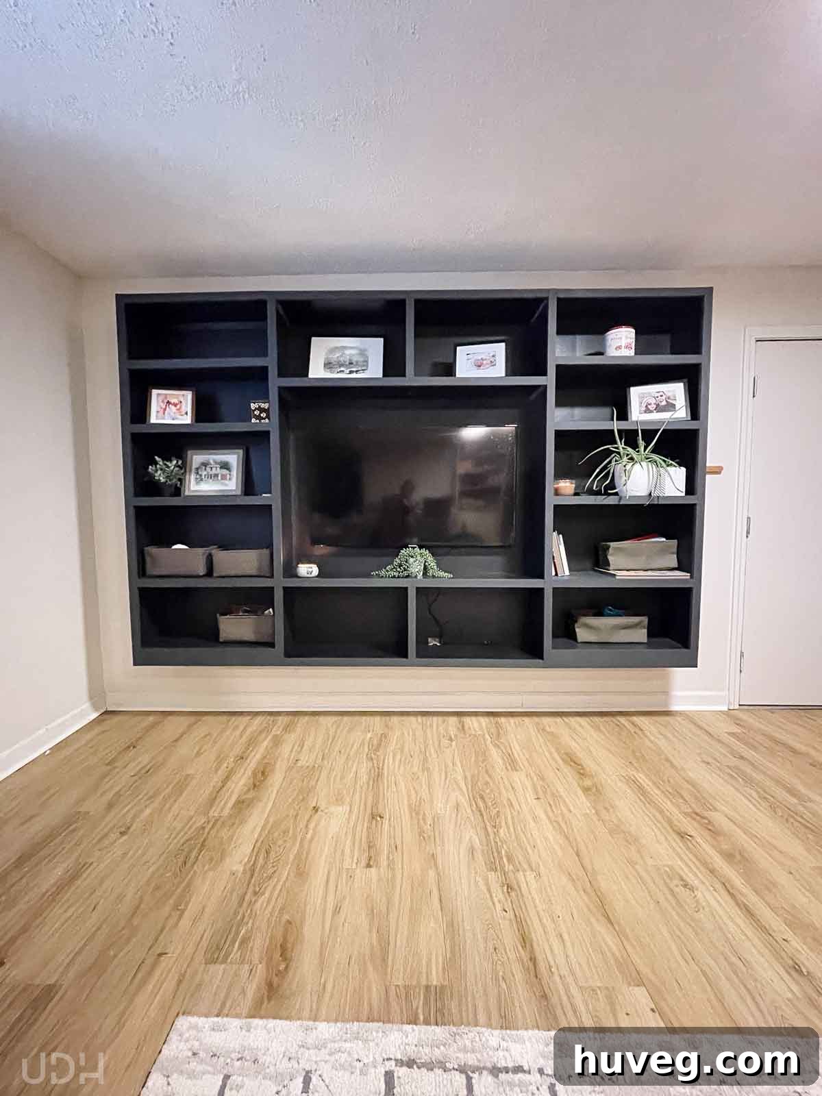 Newly painted black media wall with styled bookshelves, transforming the TV area in the basement apartment.
