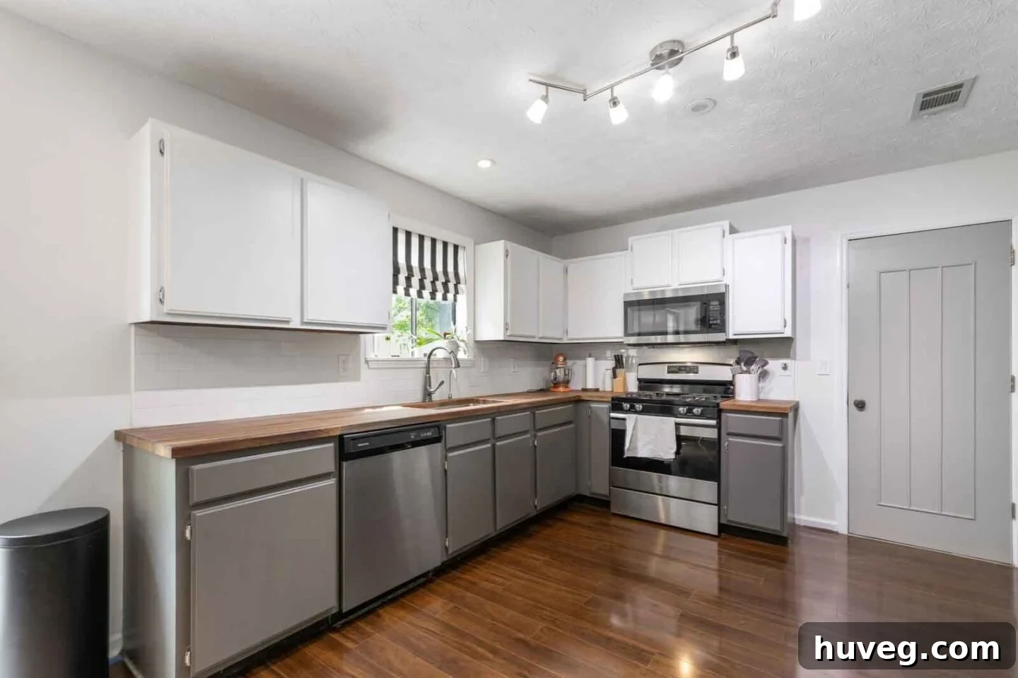 kitchen view from hallway with two tone white and gray cabinets butcher block counters and dark wood floors