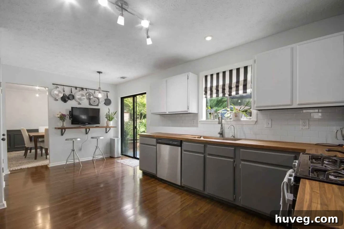 white kitchen with two tone white and gray cabinets butcher block counters and dark wood floors