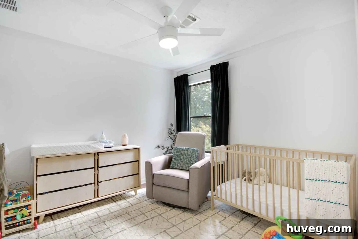 nursery with light wood white walls and dark green velvet curtains