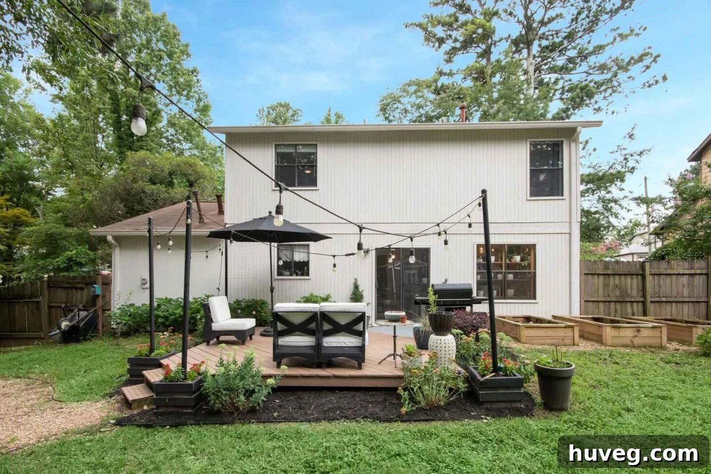 The newly painted white exterior of our house from the backyard, featuring a floating deck and decorative light pole planters.