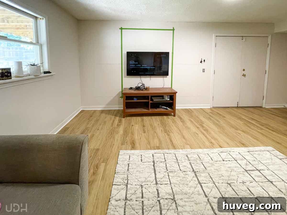 Progress shot of the basement apartment with new LVP flooring partially installed, showing significant transformation.