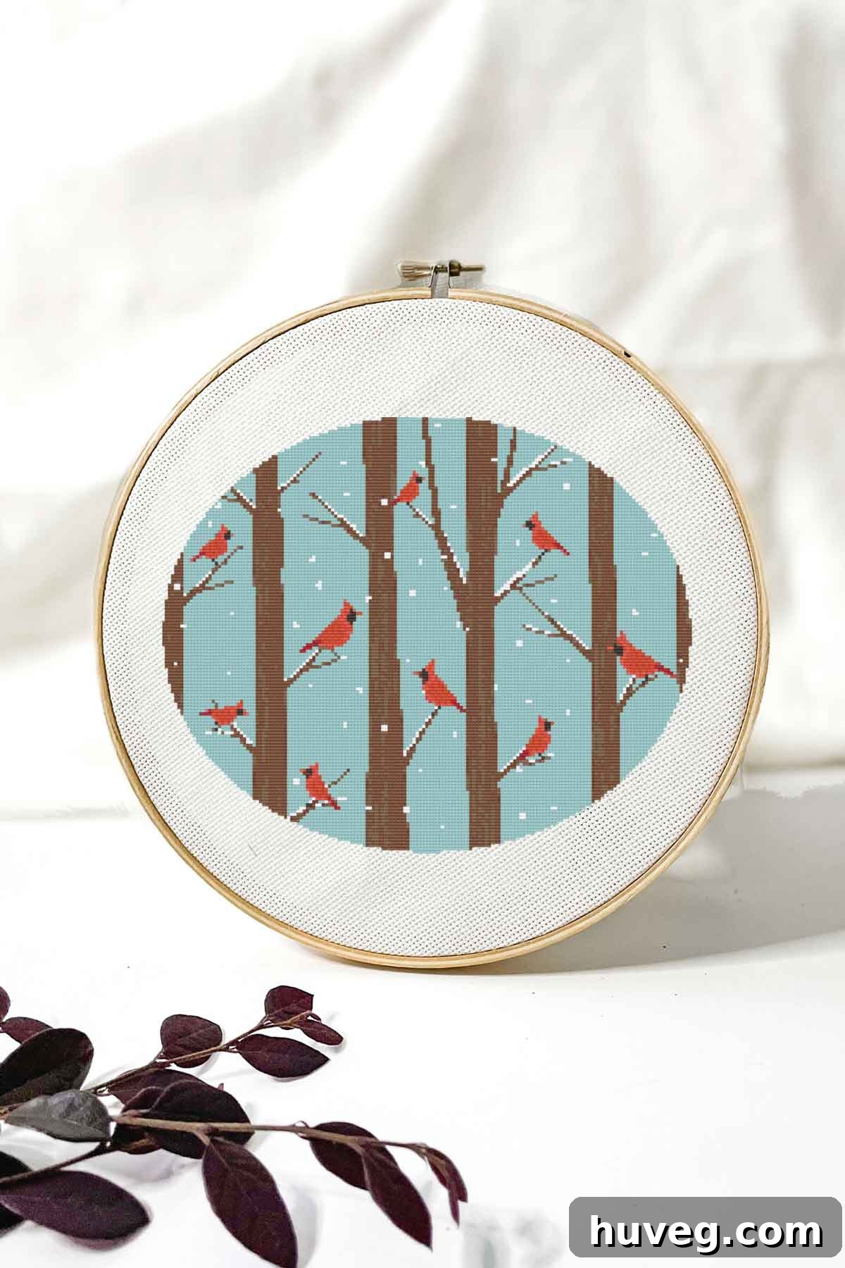 Close-up of the beautiful cardinals cross stitch pattern on white Aida fabric, highlighting intricate details.