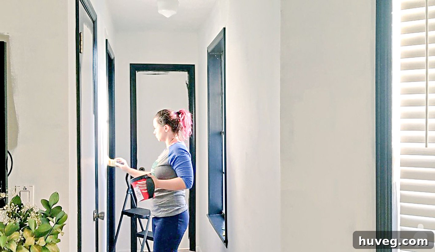 Sarah Fogle, concentrated, painting inside her master suite, showcasing her hands-on approach to home improvement and creative DIY projects.