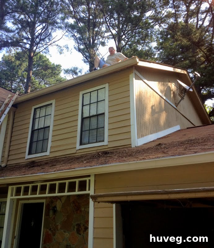 A person on a ladder cleaning a roof, highlighting home maintenance