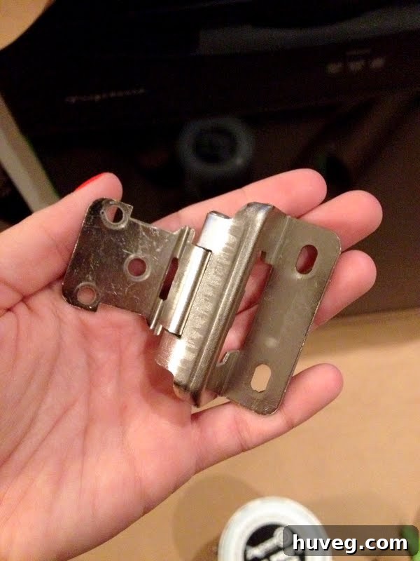 Closeup of new cabinet hinges that perfectly match existing screw holes, simplifying the kitchen renovation process.