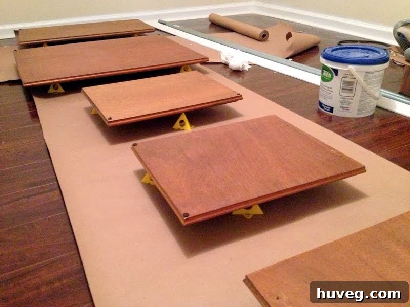 Kitchen renovation in progress with multiple upper cabinet doors spread out on tarps in the dining room for painting