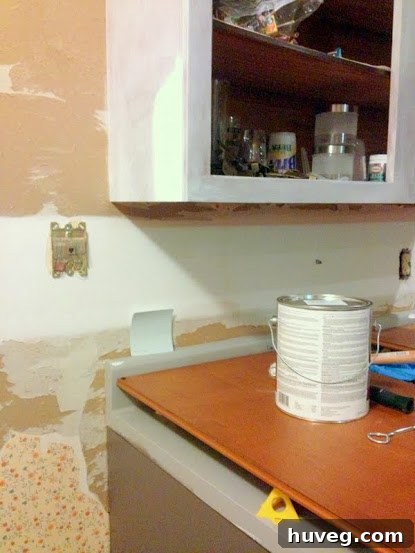 Overview of the kitchen renovation, showing primed upper cabinets and color scheme