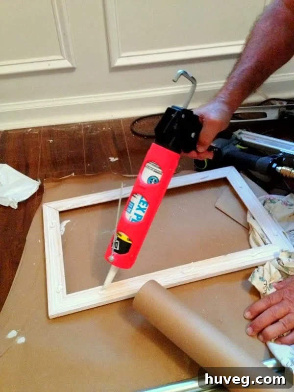 Applying a bead of caulk to the back of a molding box before installation