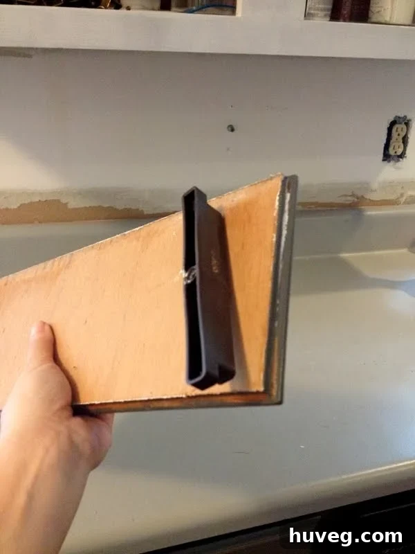 Close-up of the back of a false sink drawer front showing a poorly placed plastic turn clip at the very edge, preventing rotation.