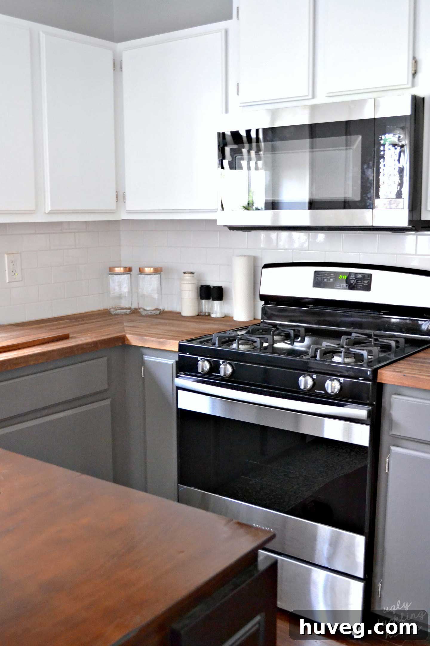 Modern kitchen with white upper cabinets, gray lower cabinets, and new stainless steel appliances