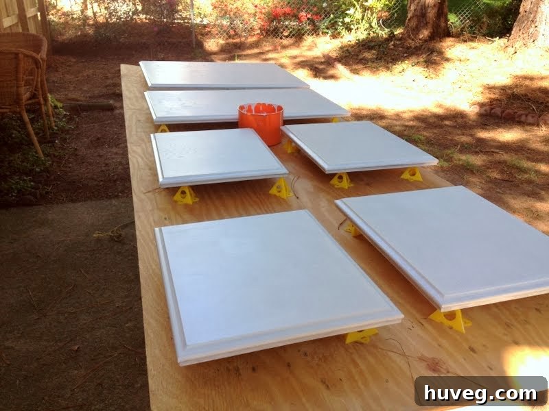 Applying additional coats of paint to kitchen cabinet doors outside