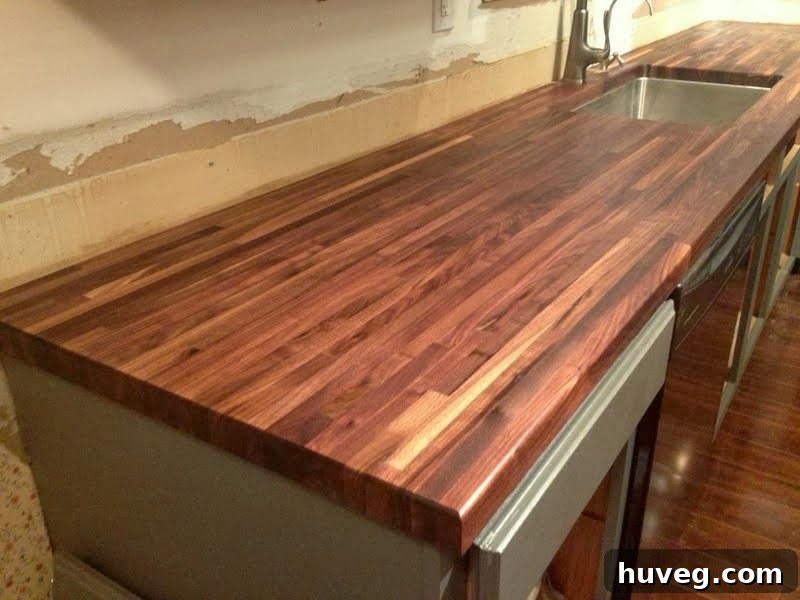 Close-up of walnut butcher block being treated with oil, showcasing the application process.