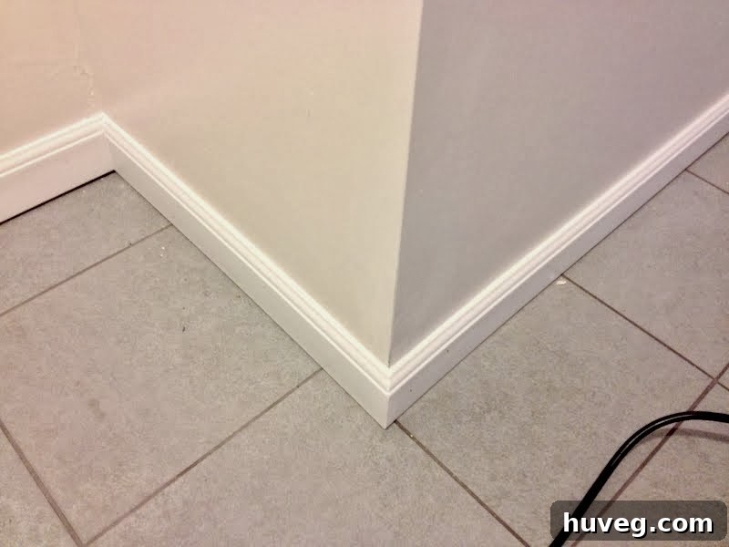 Close-up of baseboard installation and corner tile issues