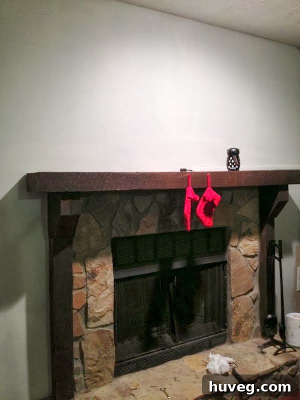 Another view of the dimly lit living room with the freshly painted white fireplace, featuring two small red Christmas stockings hung on the mantel.