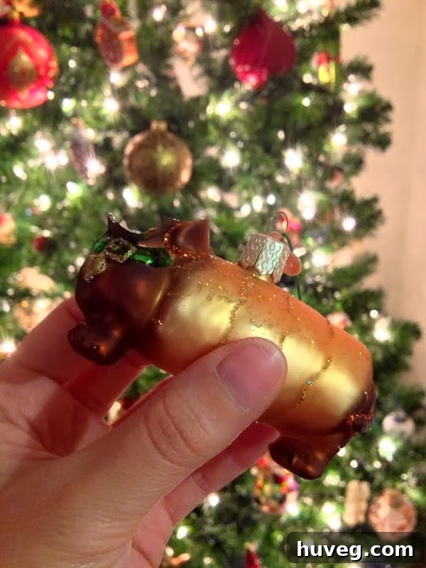 A close-up of a broken ornament on the Christmas tree, specifically a dachshund or 'weenie dog' ornament with its head missing, emphasizing a small decorating mishap.