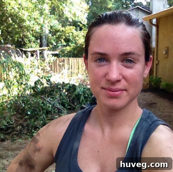 A person looking tired but satisfied after a summer of strenuous outdoor work, with removed tree branches in the background.