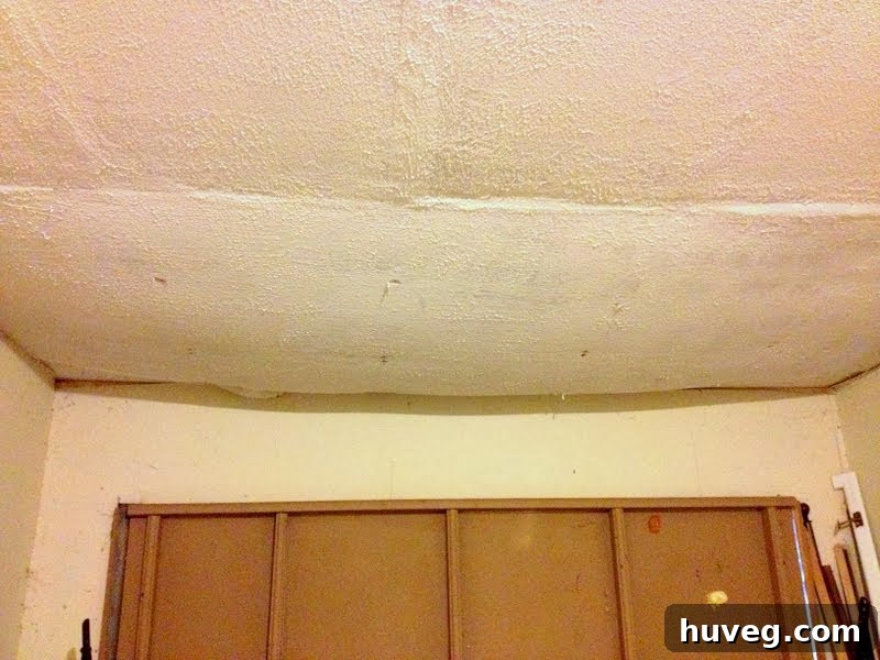 Plumber inspecting the garage ceiling where drywall has sagged due to water damage from above.
