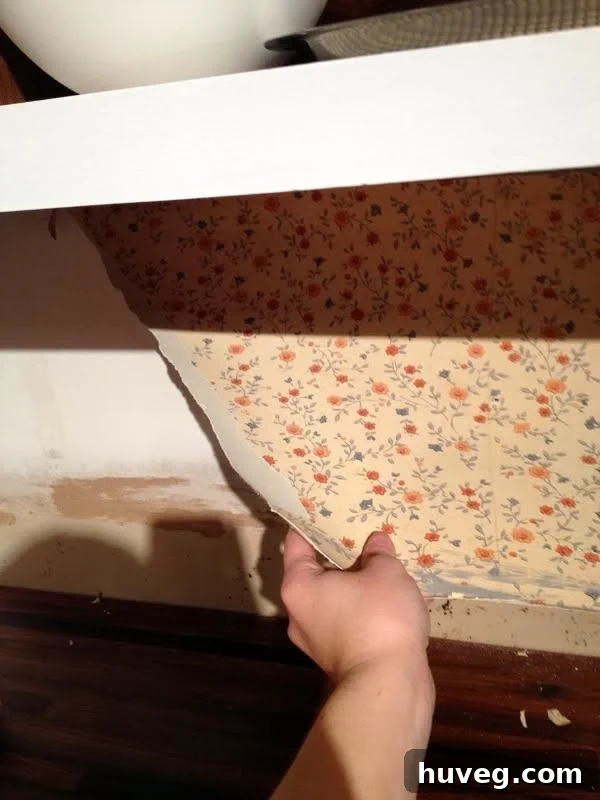 Old, stained kitchen wallpaper behind a stove