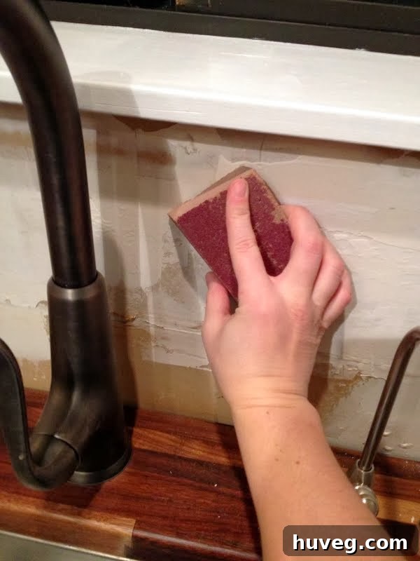 Sanding down drywall to create a smooth surface for kitchen tile backsplash