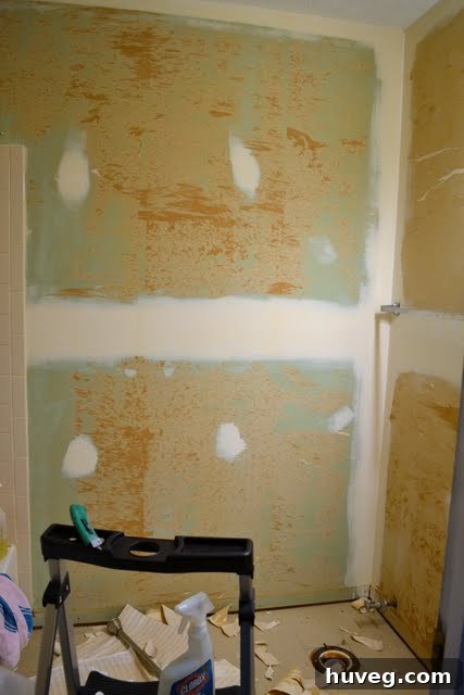 Close-up of a wall after partial wallpaper removal, showing underlying damage