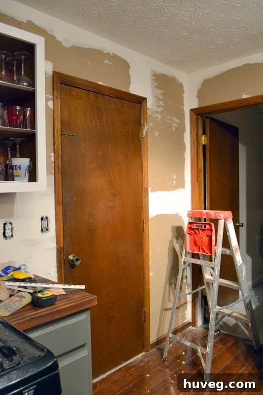 Kitchen walls after initial wallpaper removal, revealing multiple layers