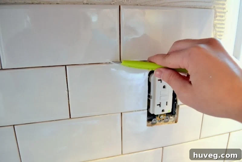 Using a craft knife to clean thinset between tiles