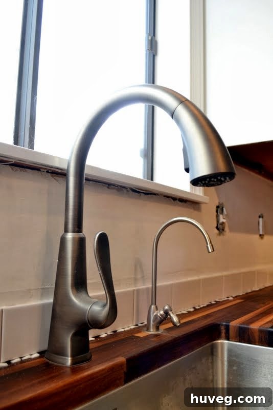 First row of subway tiles installed behind kitchen faucet